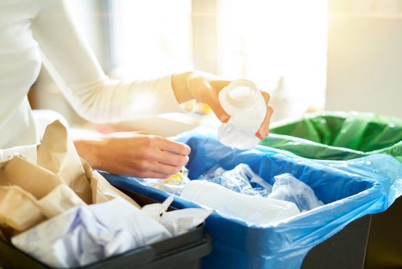 Young Woman Sorting Garbage In Kitchen.