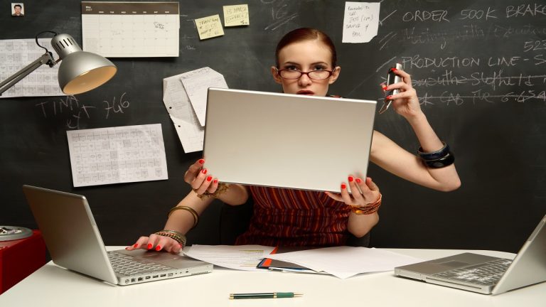 Young Woman Using Three Laptops With Four Hands, Smiling, Portrait