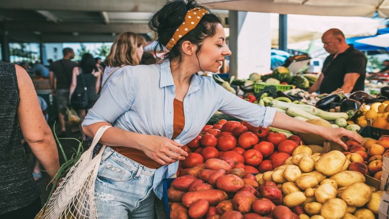 A Young Woman Buys Vegetables And Fruits At The Market .