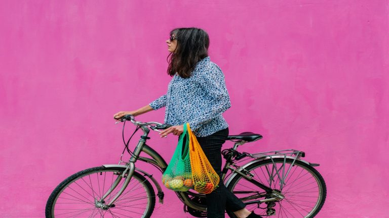 Woman With Classic Dutch Bike With Reusable Bags With A Sustainable Purchase On Pink Background