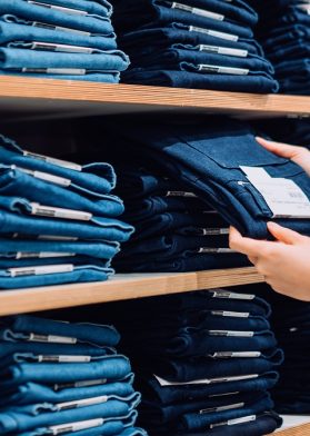 Cropped Shot Of Woman's Hand Selecting A Pair Of Trousers From The Display Shelf While Shopping In A Clothing Store In The City