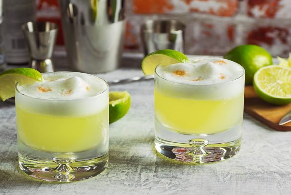 Two Pisco Sour Cocktails On The Bar With Ingredients